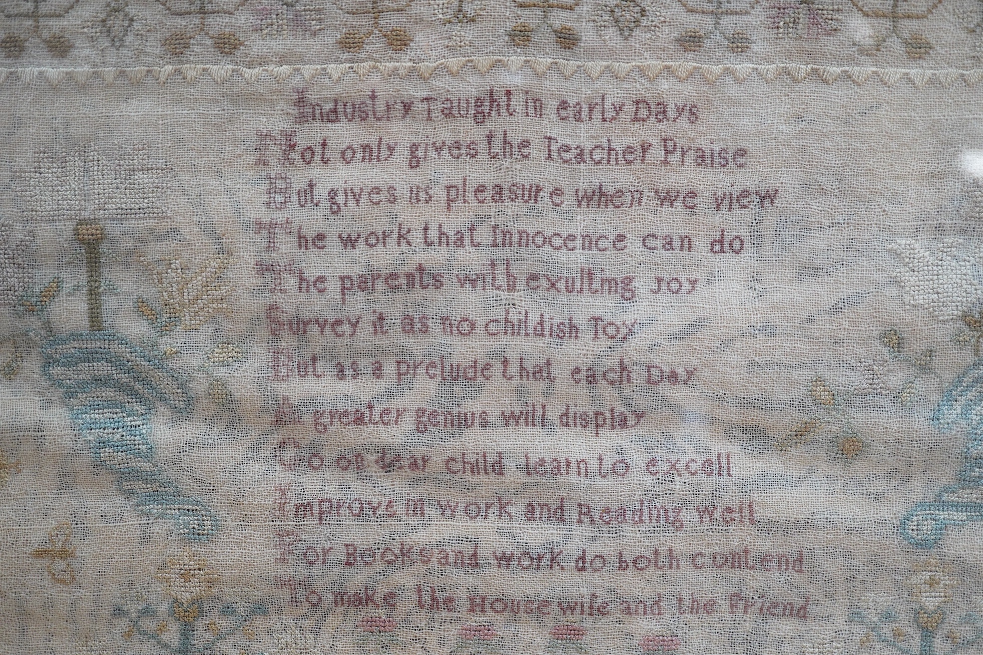 A gilt framed finely worked Regency gauze sampler, by Amelia Artus, aged 8 years, dated 1813, worked on fine gauze with coloured silk threads, with a large central panel having a long verse, two motifs of cornucopia, pot